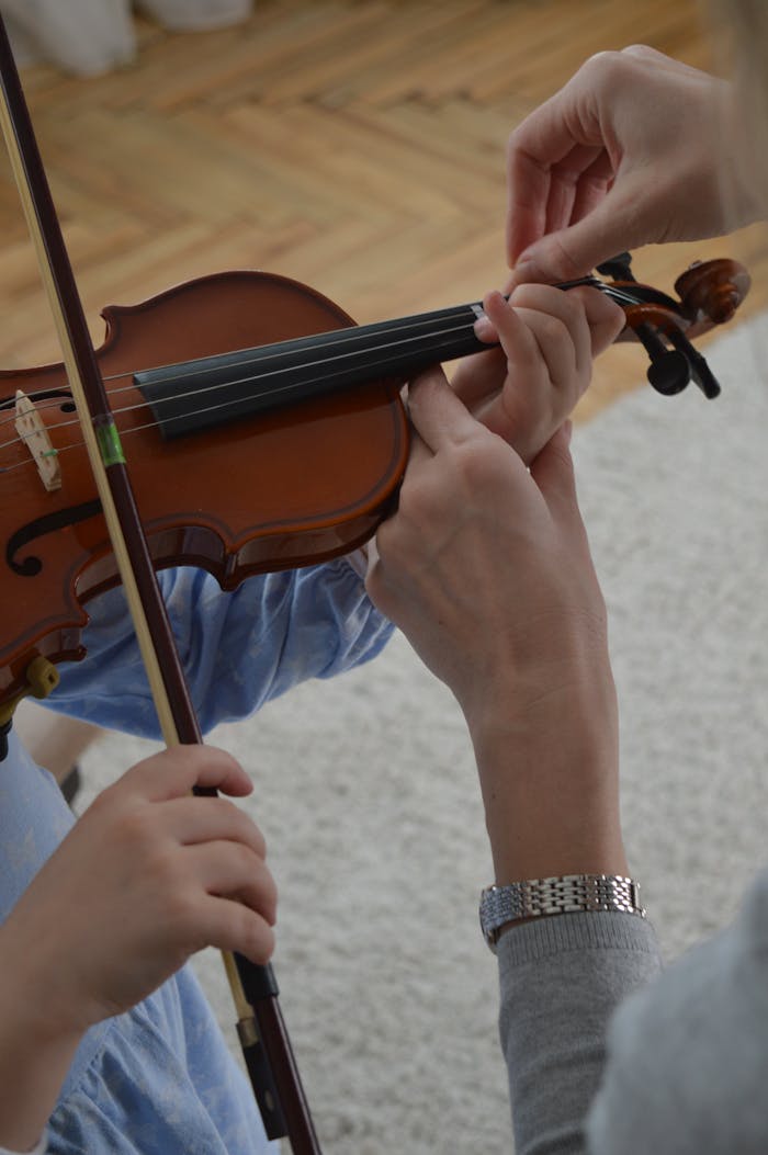 our-story-02 A child receives violin lessons from a teacher, focusing on hand positioning.